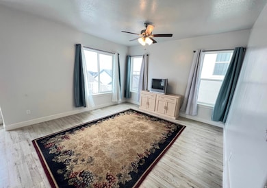 Unfurnished living room featuring a textured ceiling, plenty of natural light, light wood finished floors, and ceiling fan