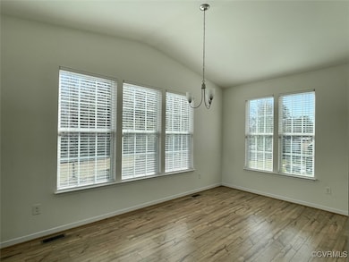 Morning room featuring vaulted ceiling, laminate w