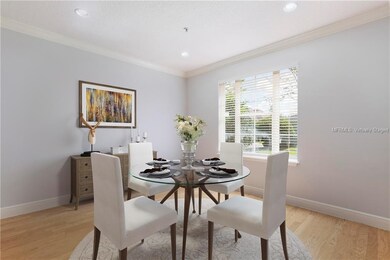 Virtually staged 12 x 11 dining room with hardwood floors, recessed lighting and crown molding is bathed in natural sunlight.