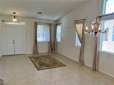 Entryway with plenty of natural light, a chandelier, lofted ceiling, and light tile patterned floors