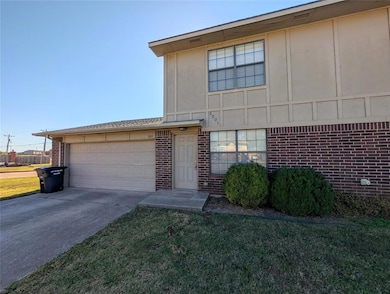 View of front facade featuring brick siding, driveway, a garage, and a front lawn