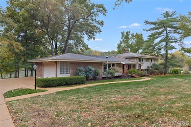 Tri-level home with brick siding, a front yard, an attached garage, and a chimney