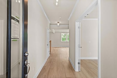 Hall with crown molding, light wood-style floors, and baseboards