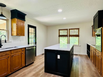Kitchen with appliances with stainless steel finishes, a sink, light wood-style flooring, light countertops, and a textured ceiling