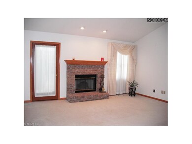 Vaulted great room with neutral carpet, gas log fireplace and access to patio