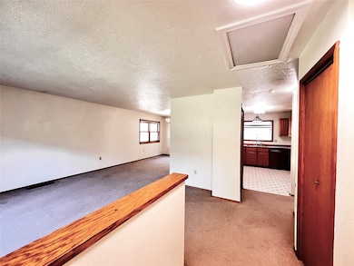 Corridor featuring light carpet and a textured ceiling
