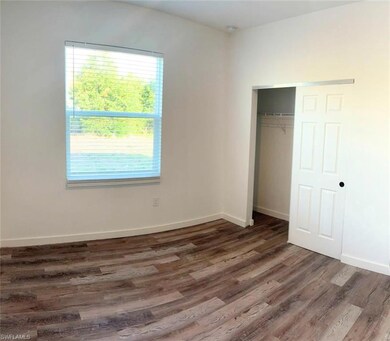 Unfurnished bedroom featuring wood finished floors, multiple windows, a closet, and baseboards