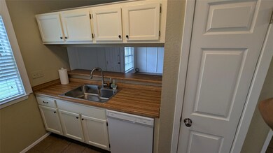 Kitchen with white dishwasher, a sink, white cabi