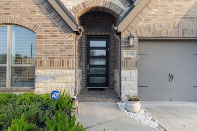 Inviting entrance of a modern brick home, featuring an elegant black door with glass panels