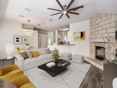 Living area virtually staged featuring a corner stone fireplace, a ceiling fan, engineered wood finished floors, a chandelier, and lofted ceiling