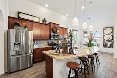 The kitchen is fitted with an oversized island, complete with bar seating, granite countertops, stainless steel appliances, and pendant lighting.