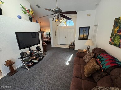 Carpeted living room featuring ceiling fan, a chan