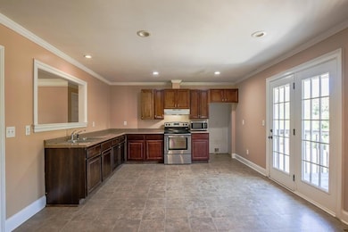 Kitchen with appliances with stainless steel finishes, ornamental molding, recessed lighting, and under cabinet range hood
