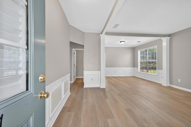 Spare room with decorative columns, a wainscoted wall, light wood-style floors, and a decorative wall