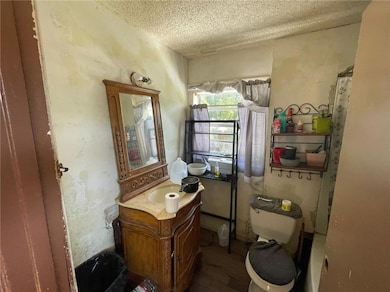 Bathroom featuring a textured ceiling, toilet, and vanity