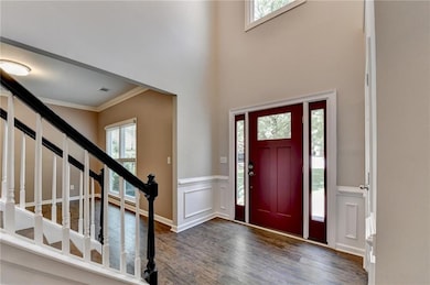 Entrance foyer featuring healthy amount of natural light, wood finished floors, ornamental molding, a wainscoted wall, and stairway