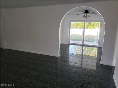 Empty room featuring arched walkways, baseboards, and ceiling fan