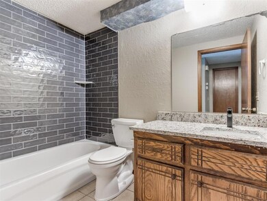 Bathroom featuring a textured wall, toilet, tile p