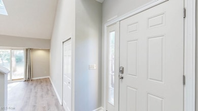 Entrance foyer with light wood finished floors, vaulted ceiling, and a skylight