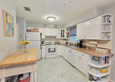 Kitchen featuring open shelves, white appliances, butcher block counters, white cabinetry, and light tile patterned flooring