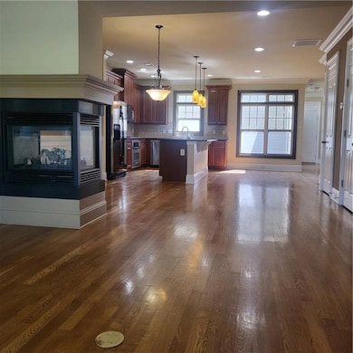 Kitchen featuring dishwasher, open floor plan, a center island, decorative backsplash, and dark wood-type flooring