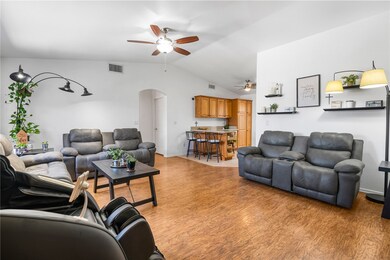 Living area with arched walkways, vaulted ceiling, light wood-type flooring, and a ceiling fan