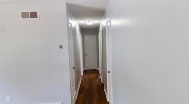 Corridor featuring dark wood-style floors and baseboards