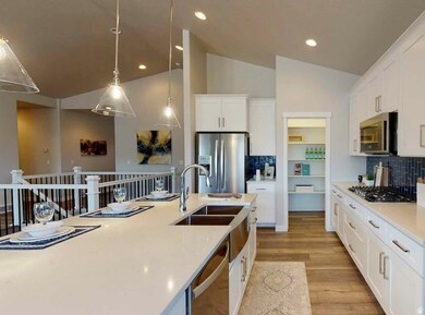 Kitchen with decorative backsplash, white cabinetry, appliances with stainless steel finishes, light wood-style floors, and lofted ceiling