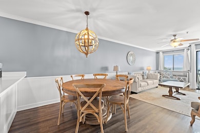 Dining area featuring wood finished floors, crown molding, a chandelier, wainscoting, and a ceiling fan