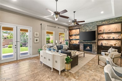 Living room featuring a raised ceiling, a stone fi