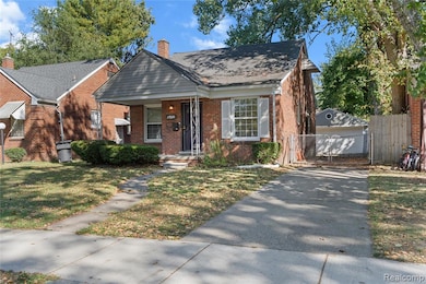 View of front of home with an outbuilding, a chimney, a porch, brick siding, and a shingled roof