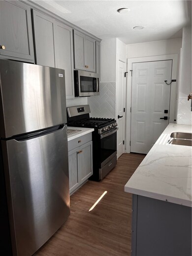 Kitchen with gray cabinets, refrigerator, gas rang