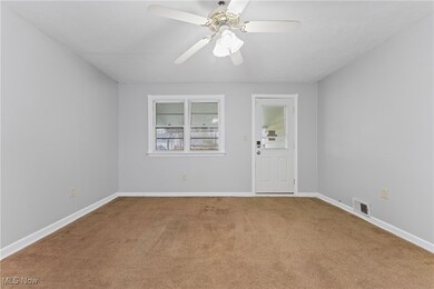 Carpeted empty room with visible vents, baseboards, and a ceiling fan