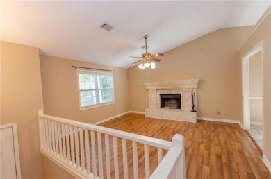 Unfurnished living room with lofted ceiling, a fireplace, hardwood flooring, and a ceiling fan