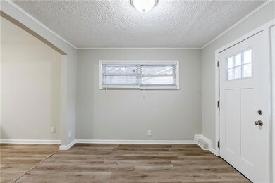 Entryway featuring light hardwood / wood-style flooring, ornamental molding, and a textured ceiling