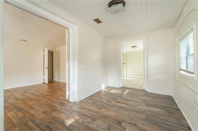 Spare room with brick wall, hardwood / wood-style floors, and wooden ceiling