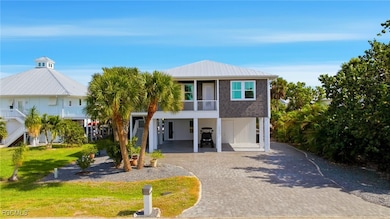 Raised beach house with a carport, decorative driveway, stairway, and a balcony