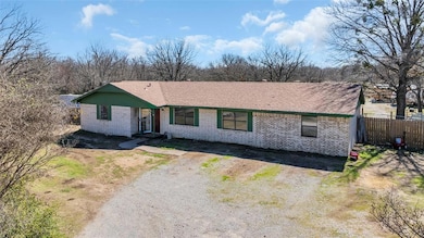 Ranch-style house with brick siding, dirt driveway, and a shingled roof