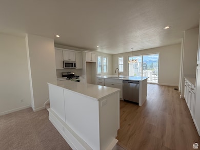 Kitchen featuring stainless steel appliances, an island with sink, a chandelier, recessed lighting, and light countertops