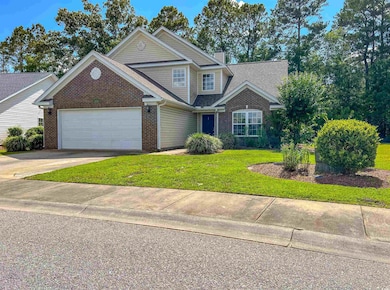Traditional-style house with brick siding, a front lawn, driveway, a garage, and a chimney