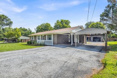 Ranch-style house featuring driveway, a front lawn, and an attached carport
