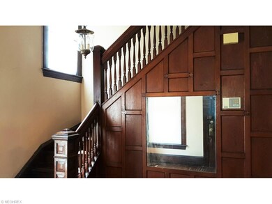 A foyer with warm wooden paneling and grand stairc