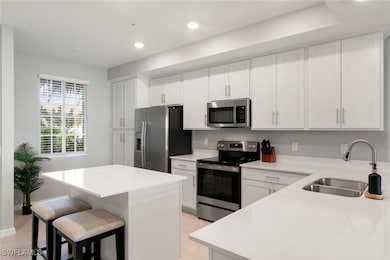 Kitchen with stainless steel appliances, white cabinetry, recessed lighting, a breakfast bar area, and a kitchen island