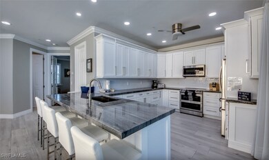 Kitchen with ceiling fan, white cabinetry, sink, k