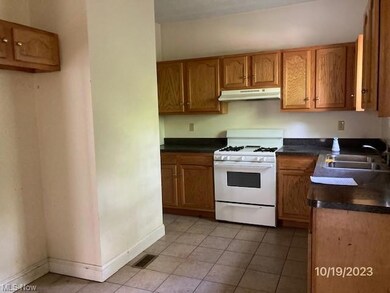 Kitchen with white gas stove, light tile floors, and sink