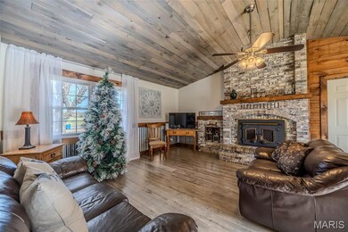 Living area featuring wood finished floors, a brick fireplace, wood ceiling, ceiling fan, and high vaulted ceiling