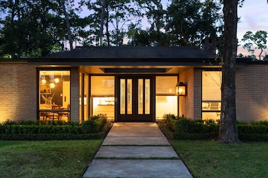 Striking original double wooden doors anchor the façade, showcasing vintage decorative glass detailing and timeless craftsmanship. Framed by mature landscaping, a colored concrete walkway, and an elegant Sheryl Stringer gas lantern, this entry sets the tone for the home’s sophisticated blend of history and modern luxury.