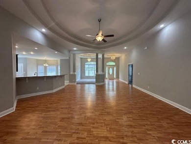 Unfurnished living room featuring a raised ceiling, a chandelier, recessed lighting, wood finished floors, and ceiling fan
