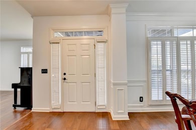 Entrance foyer featuring healthy amount of natural light, ornamental molding, and light wood-type flooring