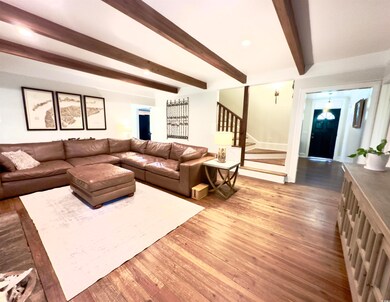 Living room with beam ceiling, stairs, and wood finished floors